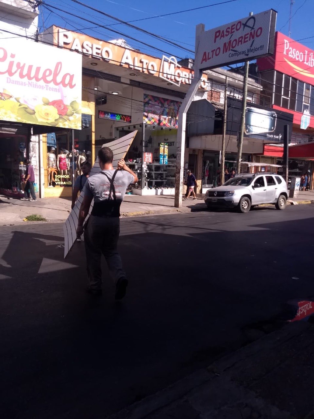 Operario trasladando una pieza en una calle comercial